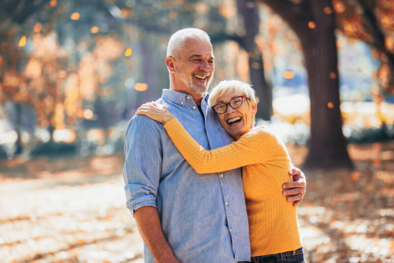 Happy older man and woman outside in falling leaves